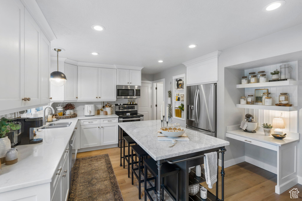 Kitchen with hardwood / wood-style floors, a kitchen island, hanging light fixtures, and stainless steel appliances