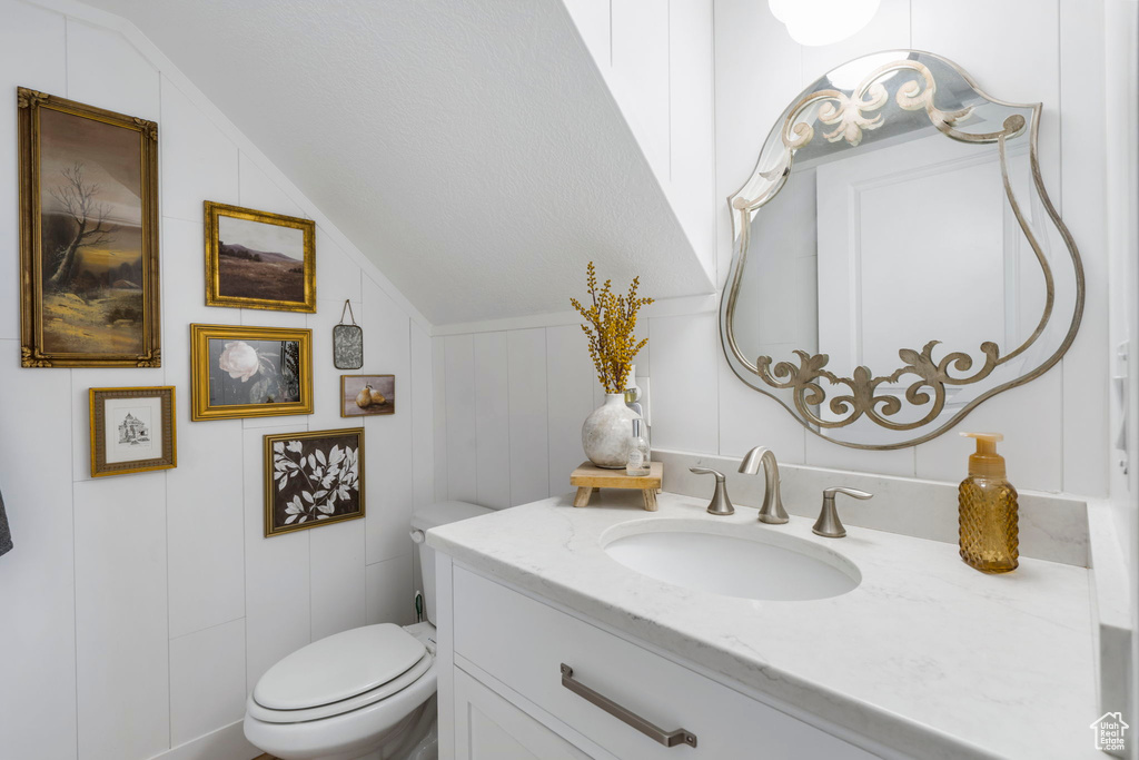 Bathroom with toilet, oversized vanity, and vaulted ceiling