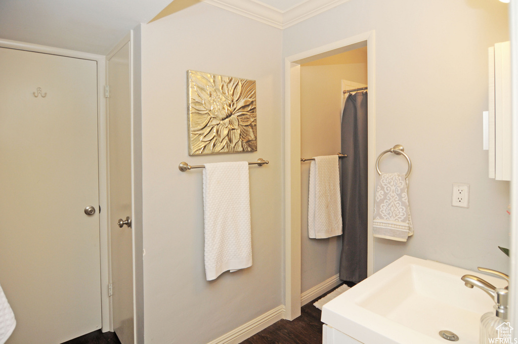 Bathroom featuring hardwood / wood-style flooring, crown molding, and sink