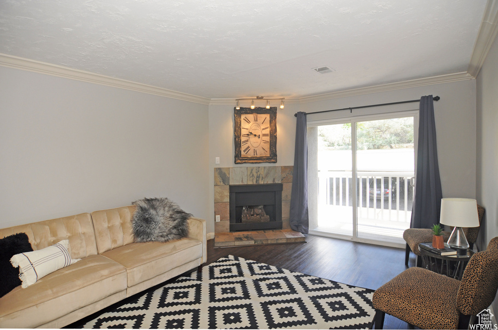 Living room with ornamental molding, dark hardwood / wood-style flooring, a tile fireplace, and rail lighting