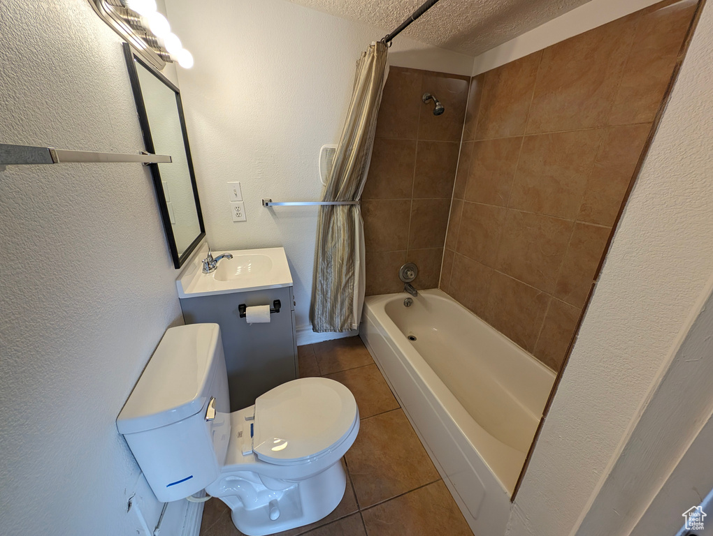 Full bathroom with large vanity, toilet, shower / bath combo with shower curtain, a textured ceiling, and tile floors