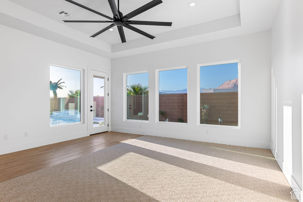 Empty room featuring a raised ceiling, ceiling fan, and hardwood / wood-style flooring