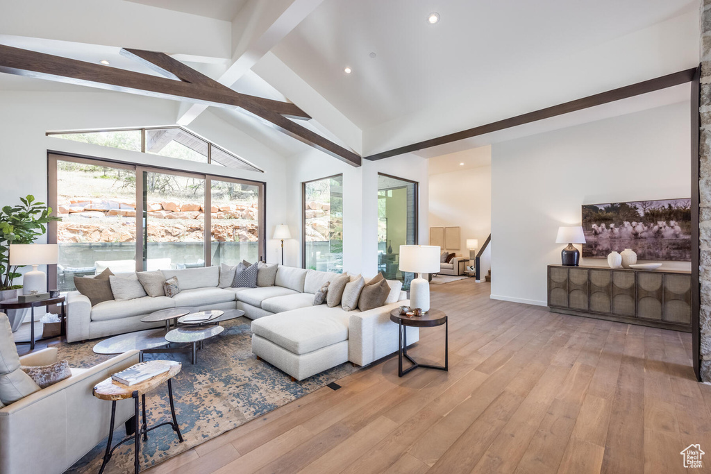 Living room with light hardwood / wood-style flooring and vaulted ceiling with beams