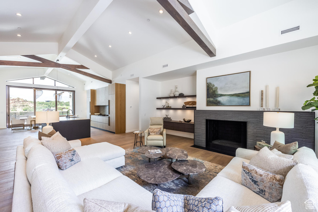 Living room with sink, lofted ceiling with beams, and light hardwood / wood-style floors