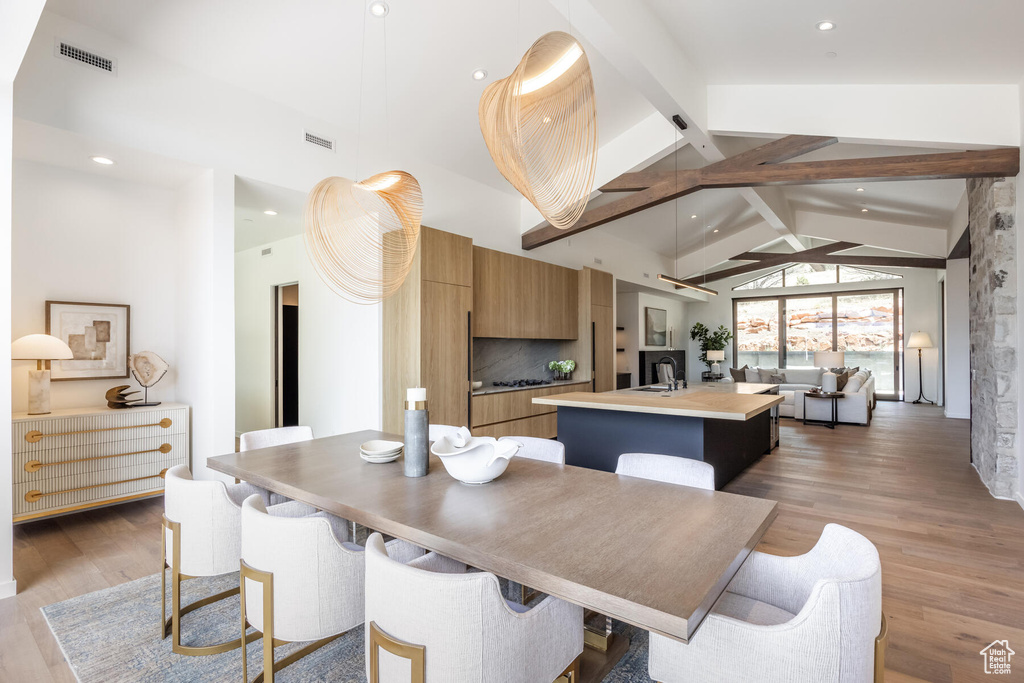 Dining room featuring beamed ceiling, high vaulted ceiling, and light hardwood / wood-style floors