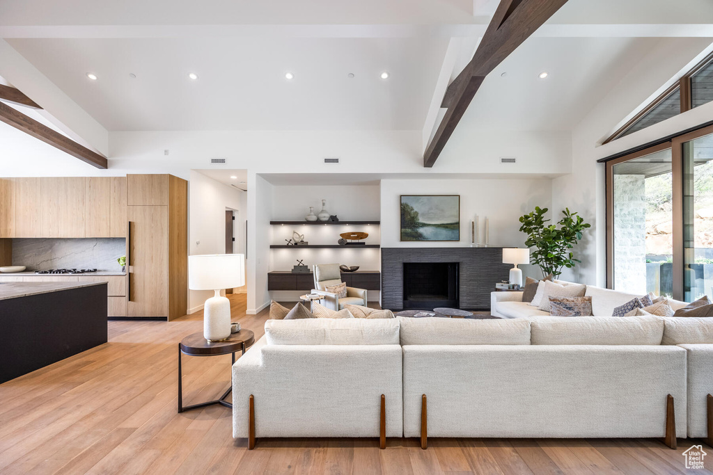 Living room with a towering ceiling, beam ceiling, and light hardwood / wood-style flooring