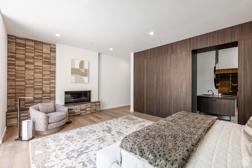 Bedroom with a large fireplace and light hardwood / wood-style floors