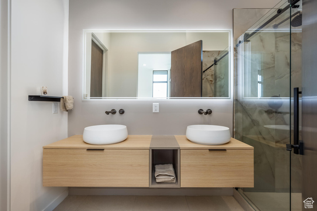 Bathroom featuring a shower with door, vanity, and tile patterned flooring