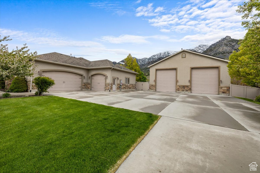 Ranch-style house featuring a mountain view, a garage, and a front lawn