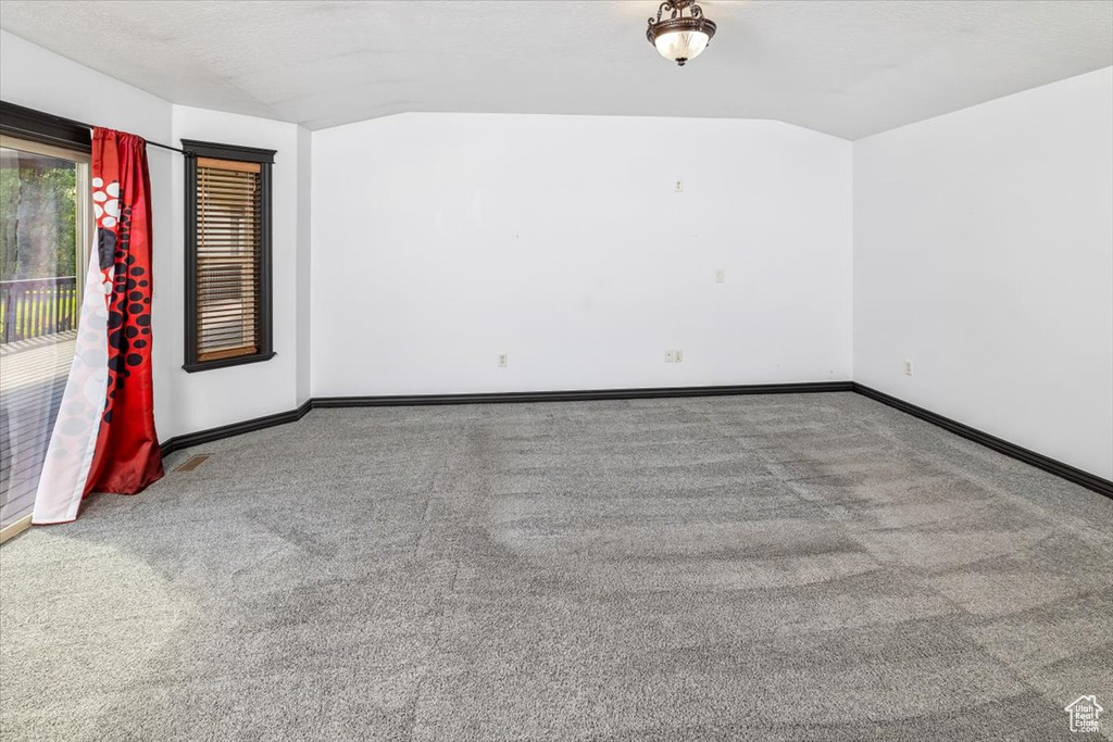 Empty room featuring carpet floors and lofted ceiling