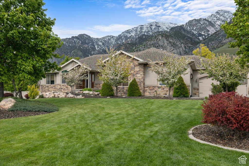 View of front of property with a garage, a mountain view, and a front lawn