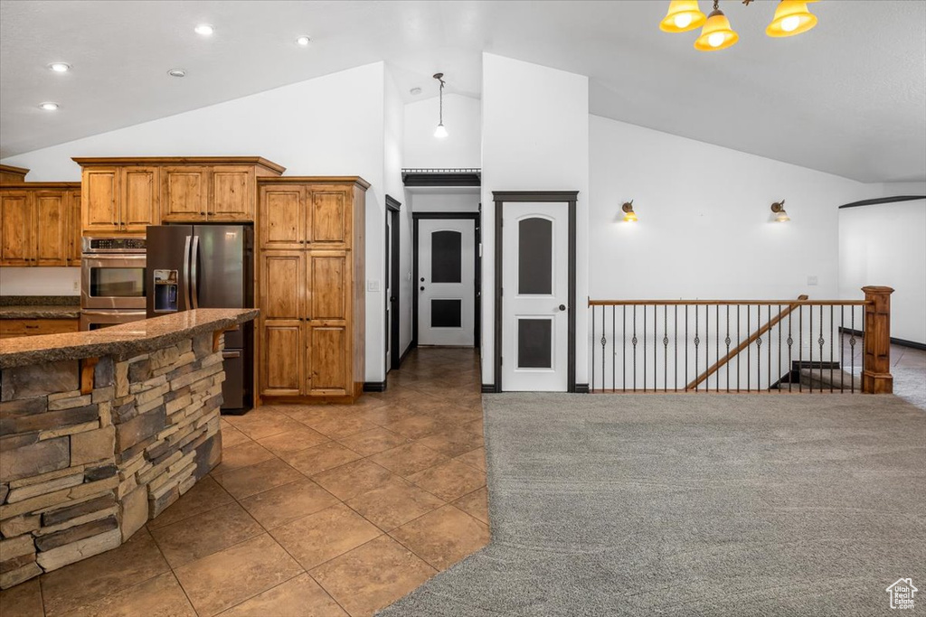 Kitchen featuring appliances with stainless steel finishes, decorative light fixtures, high vaulted ceiling, a breakfast bar area, and a chandelier