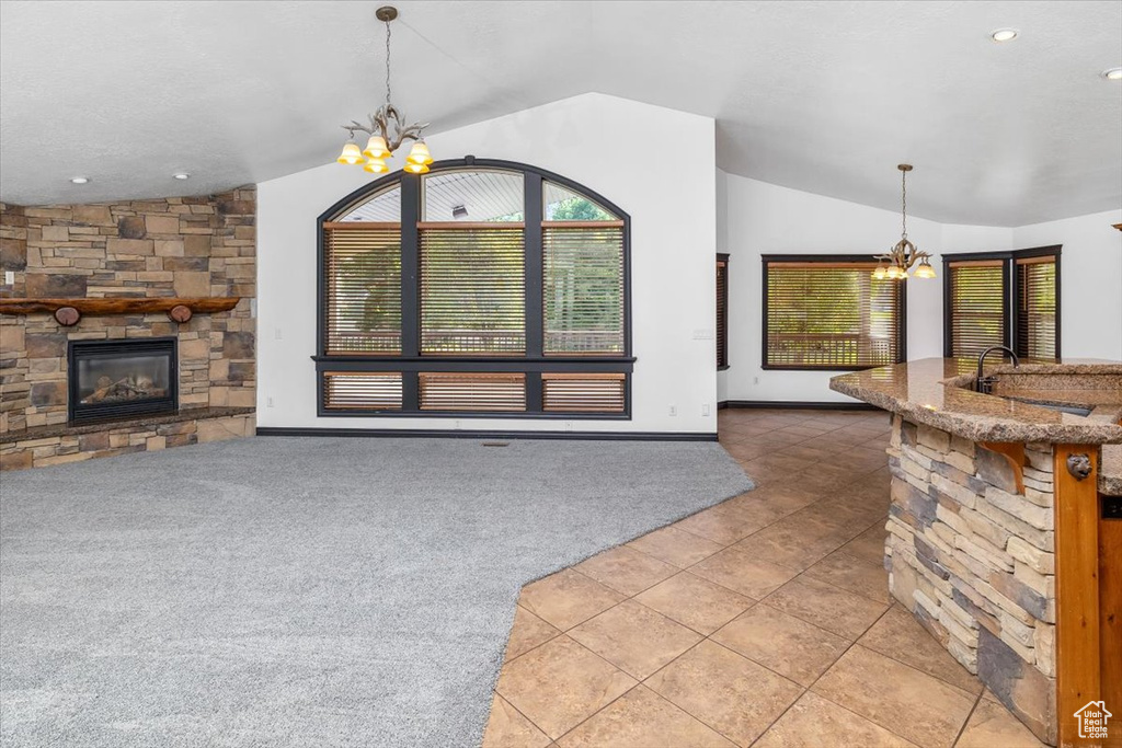 Unfurnished living room with a chandelier, sink, lofted ceiling, and tile flooring