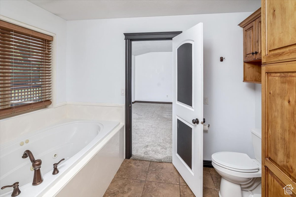 Bathroom featuring tile flooring, tiled bath, and toilet