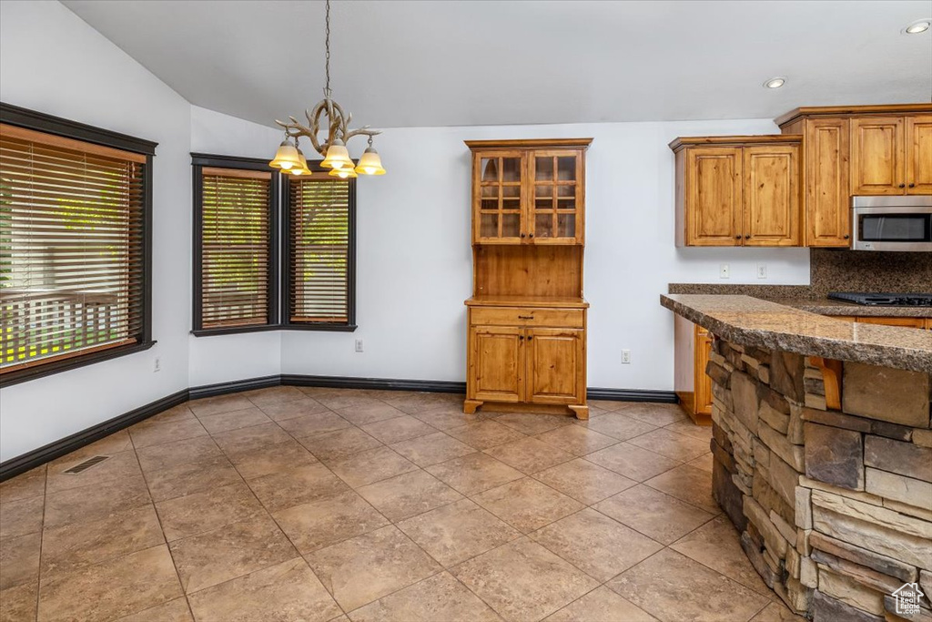 Kitchen featuring hanging light fixtures, lofted ceiling, light tile flooring, and backsplash