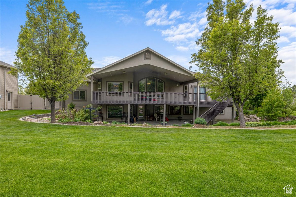 Back of property with a patio area, a yard, and a wooden deck