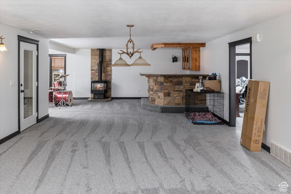 Carpeted living room with a wood stove and a textured ceiling