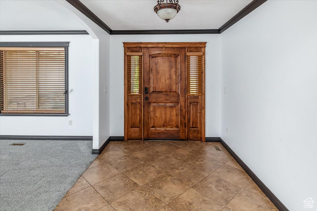 Carpeted entrance foyer featuring ornamental molding