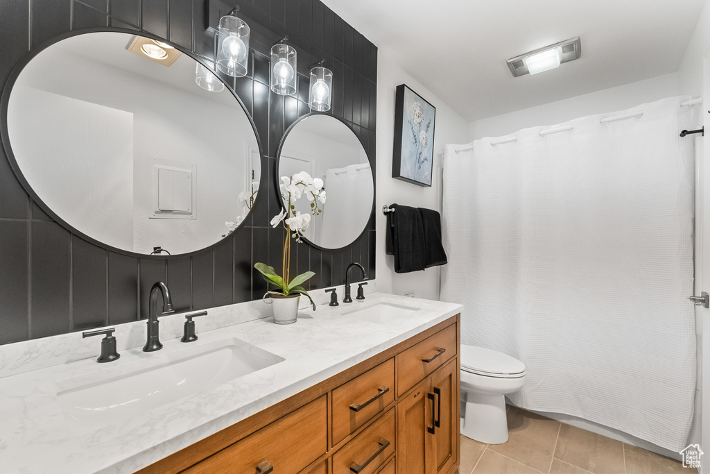 Bathroom with tile flooring, toilet, and dual bowl vanity