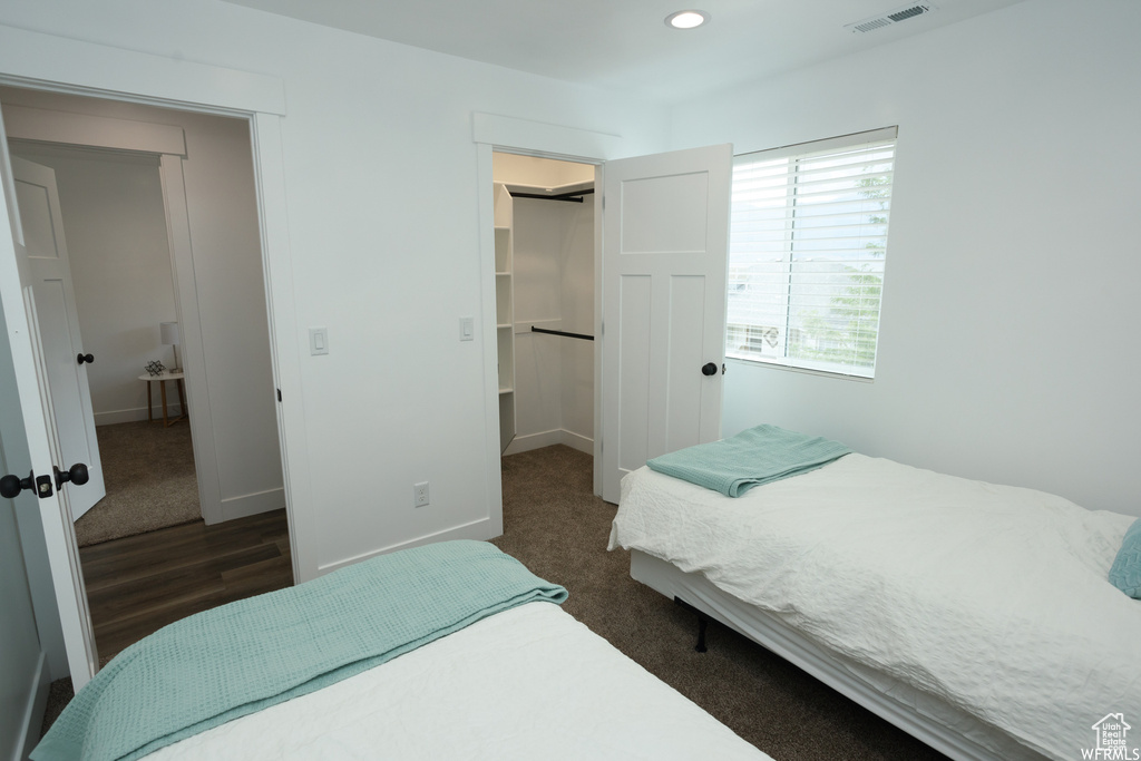 Bedroom featuring a walk in closet, a closet, and dark hardwood / wood-style floors