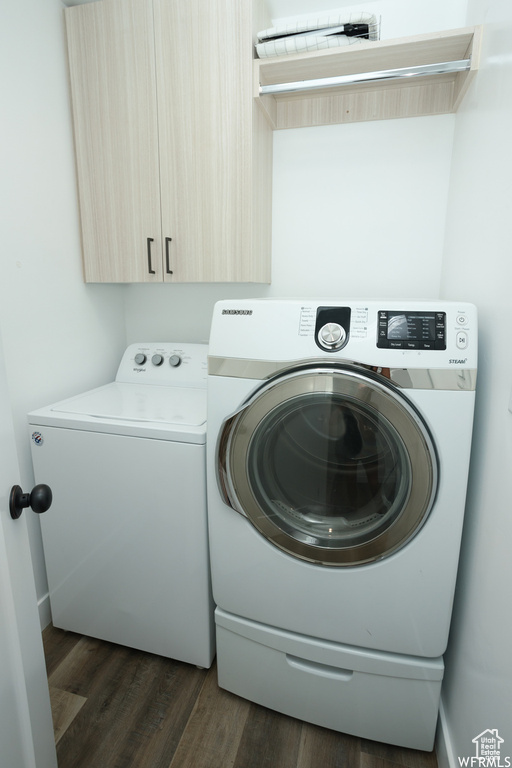 Laundry room with cabinets, dark hardwood / wood-style flooring, and washing machine and dryer