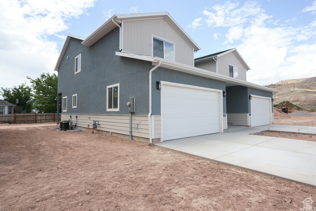 View of side of home with a garage and central air condition unit