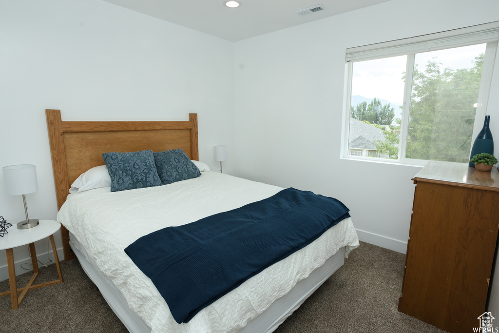 Bedroom featuring dark carpet and multiple windows