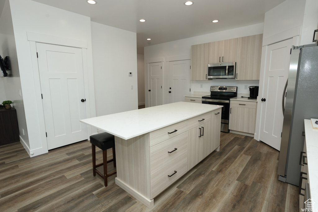 Kitchen with a center island, radiator heating unit, a breakfast bar, dark wood-type flooring, and stainless steel appliances