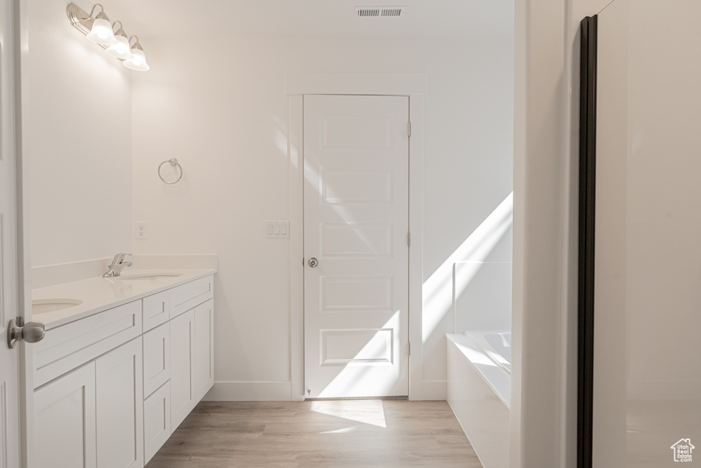 Bathroom with vanity, a bathtub, and wood-type flooring