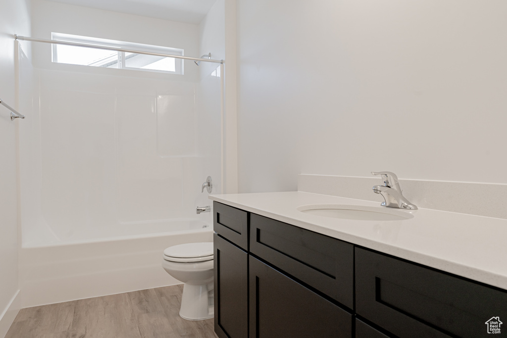 Full bathroom featuring vanity, toilet, shower / washtub combination, and hardwood / wood-style flooring