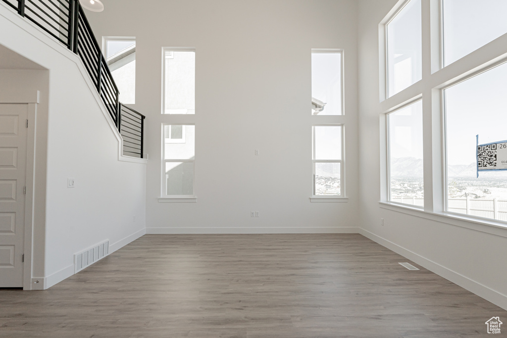 Unfurnished living room with a high ceiling and light wood-type flooring