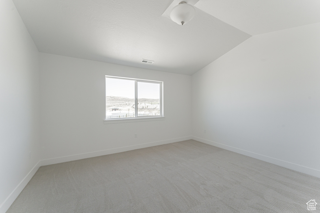 Carpeted spare room with vaulted ceiling