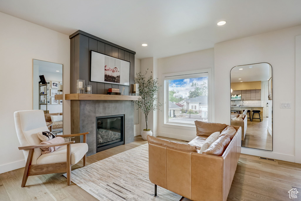 Living room with light hardwood / wood-style flooring and a large fireplace