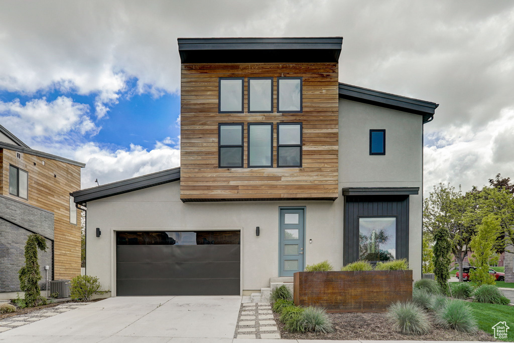 Contemporary house with central AC unit and a garage