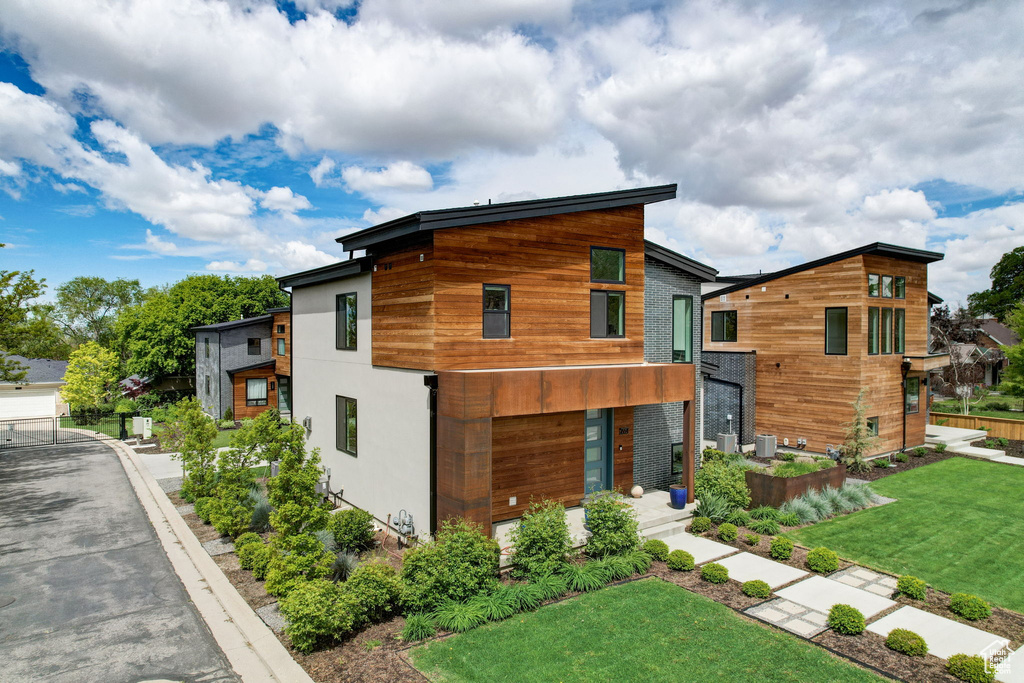 Modern home with a front lawn, a balcony, and central AC