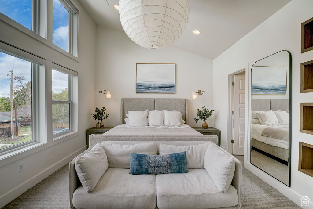 Carpeted bedroom with vaulted ceiling and multiple windows