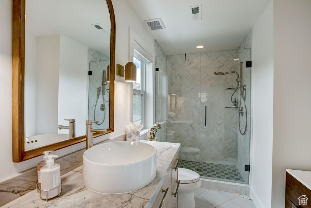 Bathroom with an enclosed shower, toilet, tile floors, and vanity