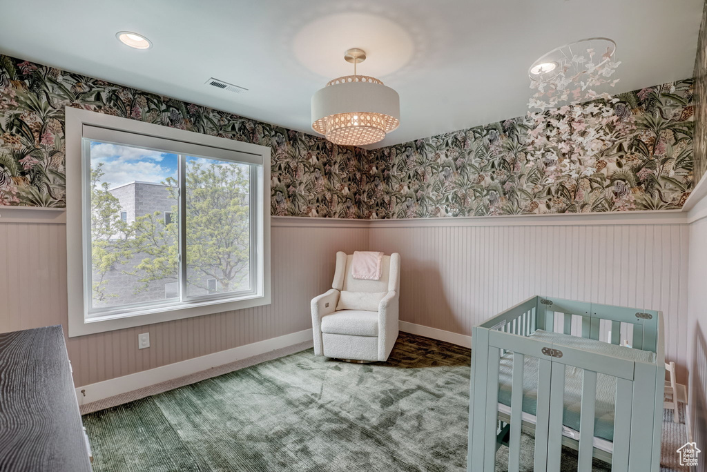 Bedroom with carpet flooring, a notable chandelier, a crib, and multiple windows