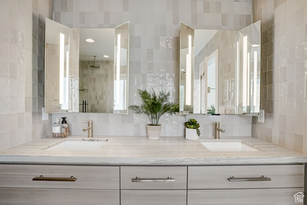 Bathroom featuring tasteful backsplash, double vanity, and tile walls