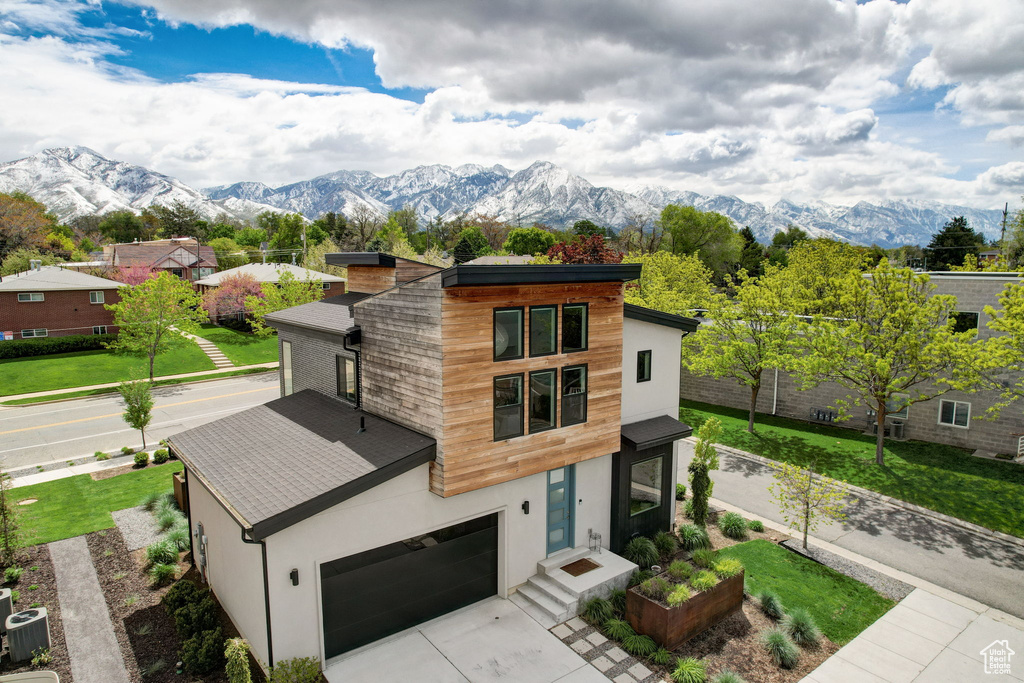 View of front of home with a mountain view, a garage, a front lawn, and central air condition unit