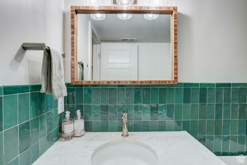 Bathroom featuring tile walls, tasteful backsplash, and vanity with extensive cabinet space