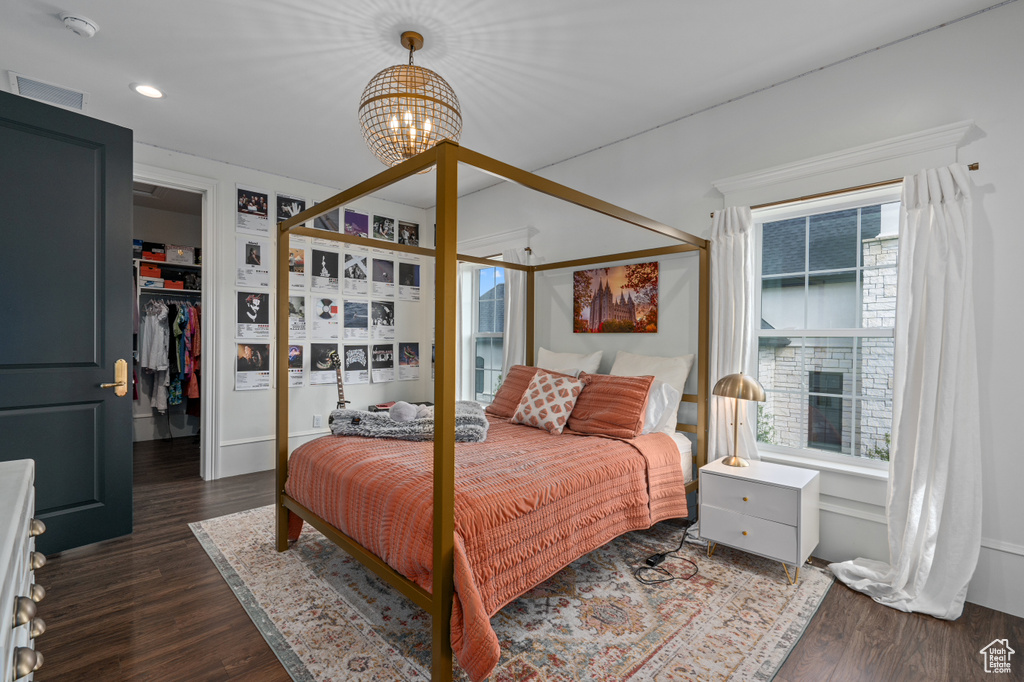 Bedroom with a spacious closet, dark hardwood / wood-style flooring, and a chandelier