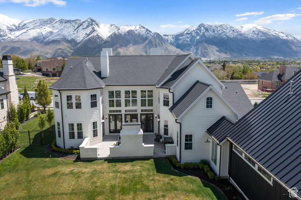 Back of house with a patio area, a mountain view, and a lawn