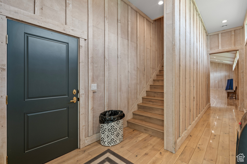 Entryway with wooden walls and light wood-type flooring