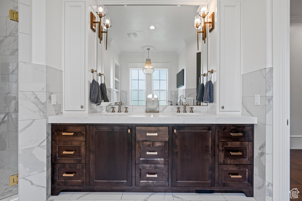 Bathroom with tile walls, dual bowl vanity, tile flooring, and crown molding