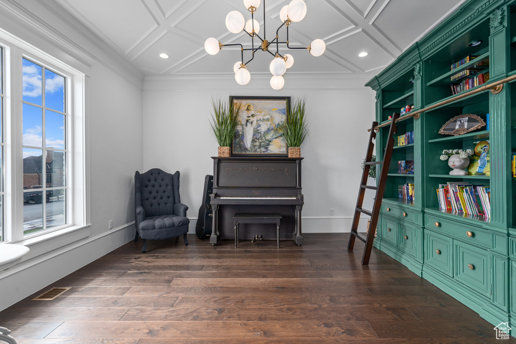 Living area with dark wood-type flooring, crown molding, coffered ceiling, and a notable chandelier