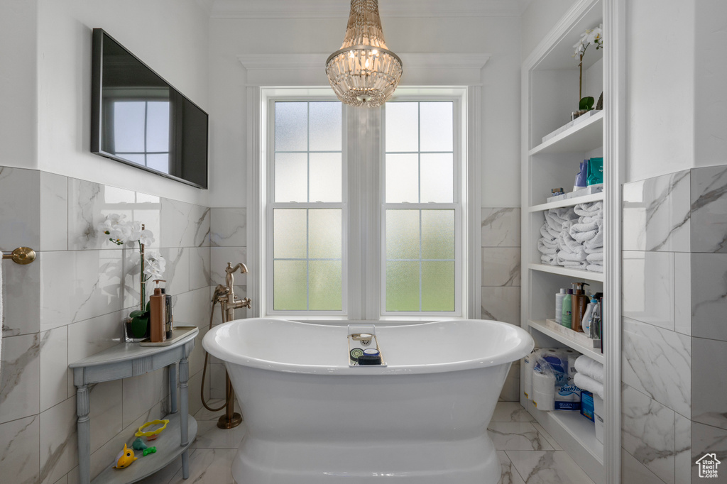 Bathroom with a washtub, tile floors, tile walls, and a chandelier