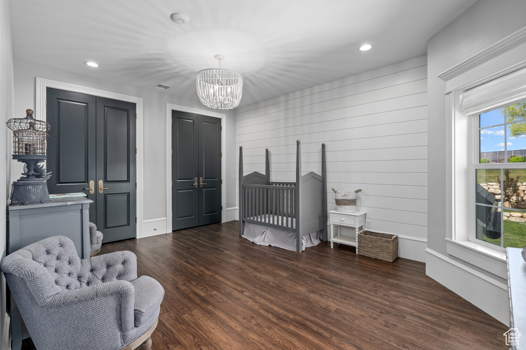 Sitting room featuring dark wood-type flooring, a chandelier, and wooden walls