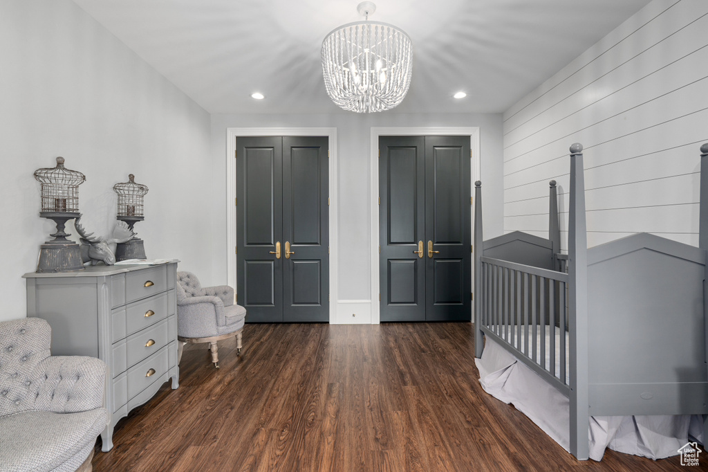 Bedroom with a chandelier, a nursery area, and dark wood-type flooring