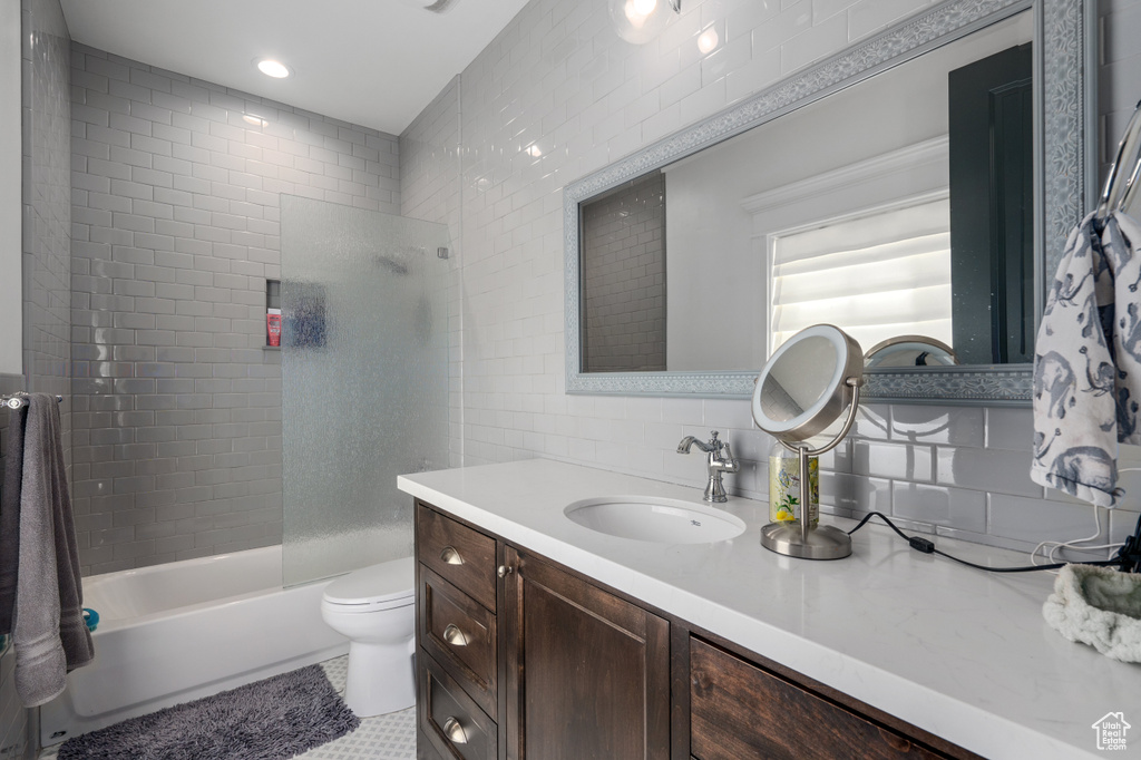 Full bathroom featuring tile flooring, tile walls, tasteful backsplash, toilet, and vanity